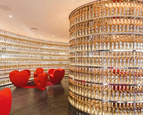 The hotel's Whisky Bar is carved into the lobby, with an undulating wall of over 2,000 custom whisky bottles featuring labels sculpted and stamped out of metal bathing the space in a bronze glow / The Watergate Hotel