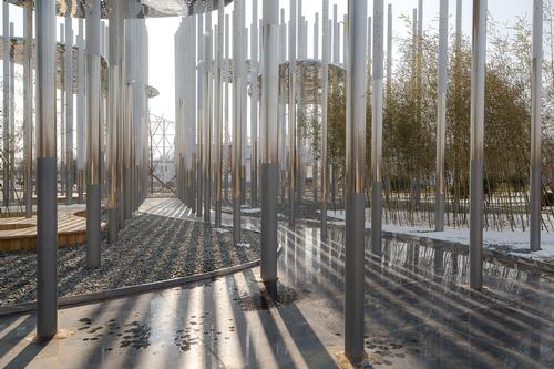 The lower sections of the poles are mirrored and undulate as one, giving the sense of a river flowing through the base of the installation / Aurelien Chen
